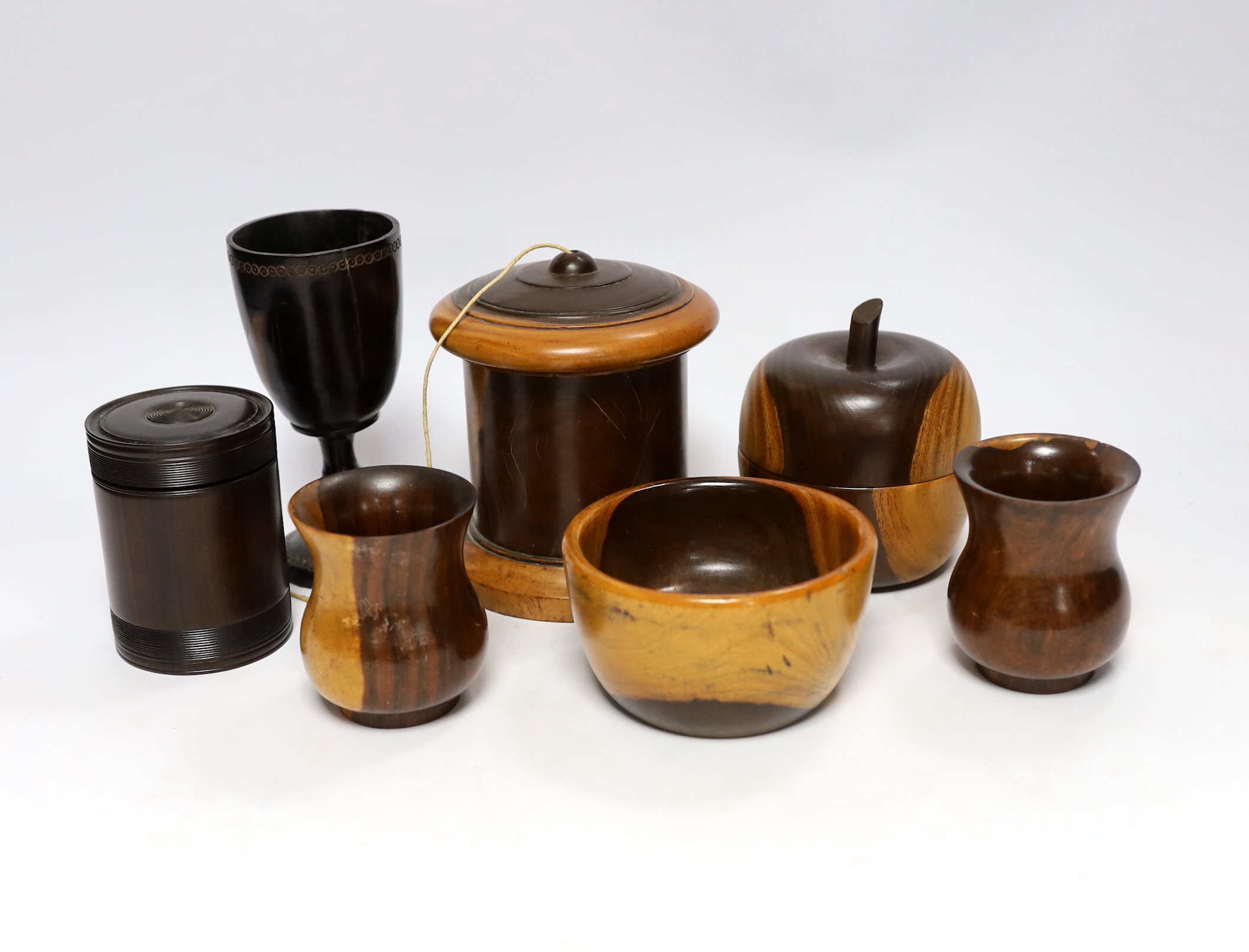 A collection of 19th/20th century lignum vitae vessels, including a turned string box and cover, an apple shaped box and cover, two vases, a mortar, a goblet and a box and cover (7)